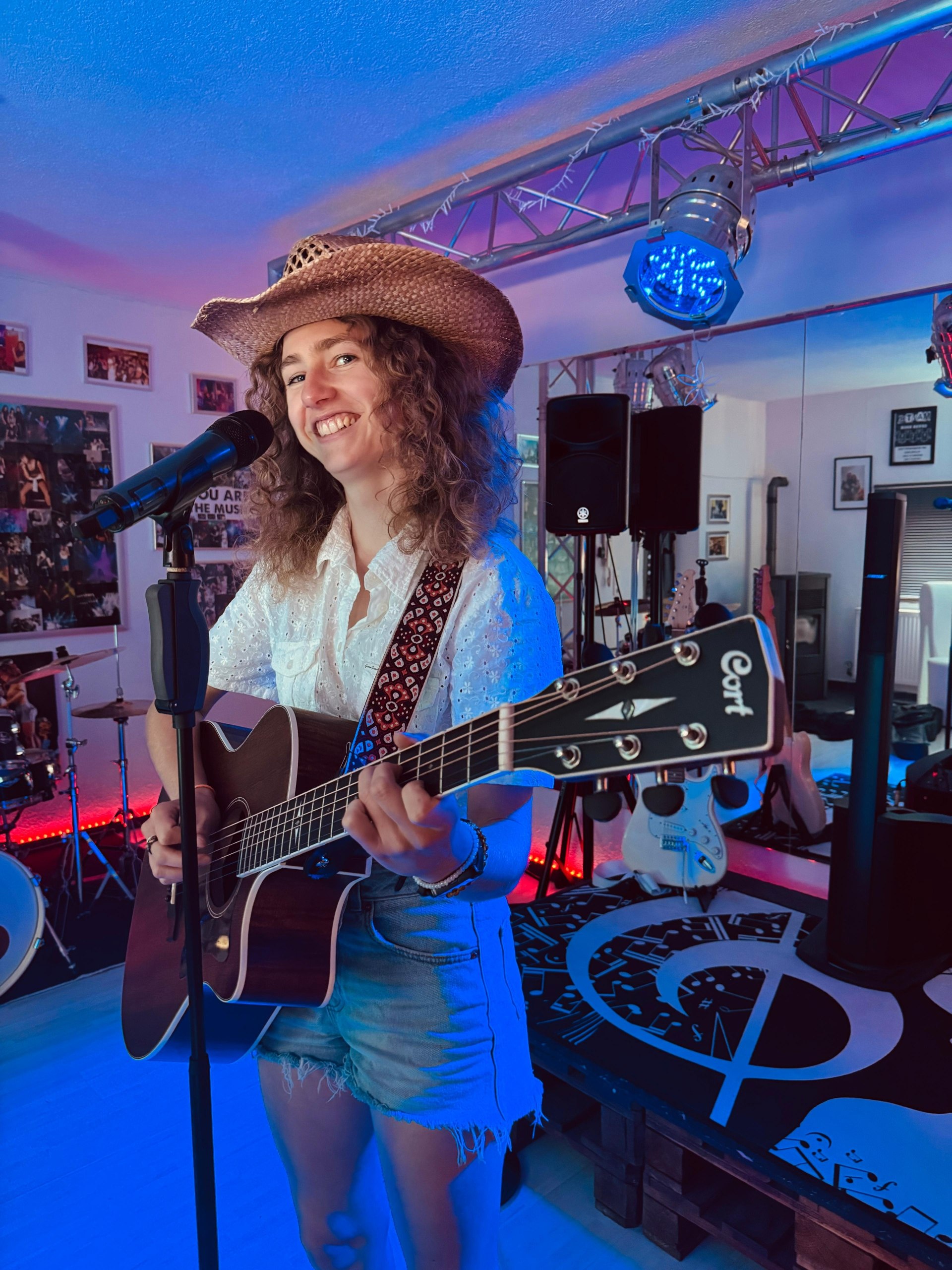 Amy mit Cowboyhut und Gitarre auf der Bühne